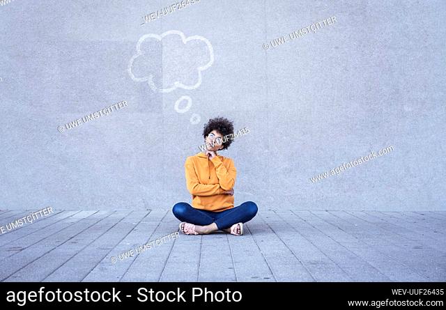 Woman sitting cross-legged on ground with empty thought bubble