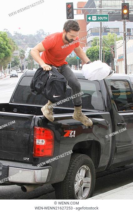 A bearded Shia LaBeouf wearing his favourite old red 'Mighty Alpha Superstars 1981-1982' t-shirt jumps down from the back of a pickup truck carrying a Nike...