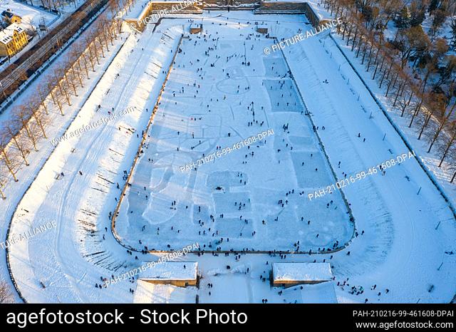 13 February 2021, Saxony, Leipzig: Leipzigers skate across the ice on the Lake of a Thousand Tears in front of the Monument to the Battle of the Nations