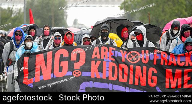 31 July 2021, Schleswig-Holstein, Brunsbüttel: Participants in a demonstration with a banner reading ""LNG? Are you fracking kidding me?!""