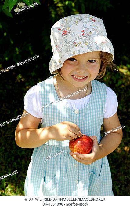 Little girl in the summer with an apple