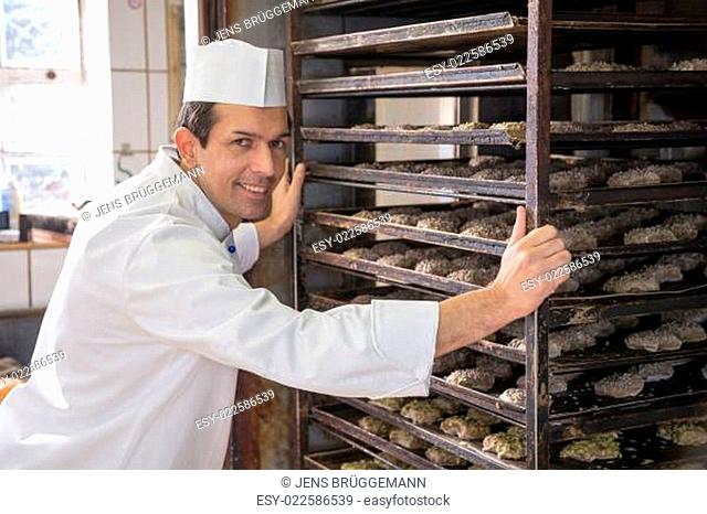 Baker putting a rack of bread into oven