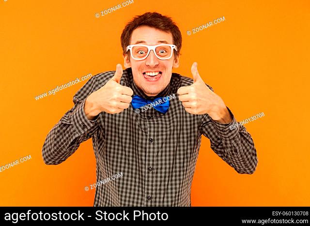 Crazy scentist tongue out and thumbs up. Studio shot. Isolated on orange background