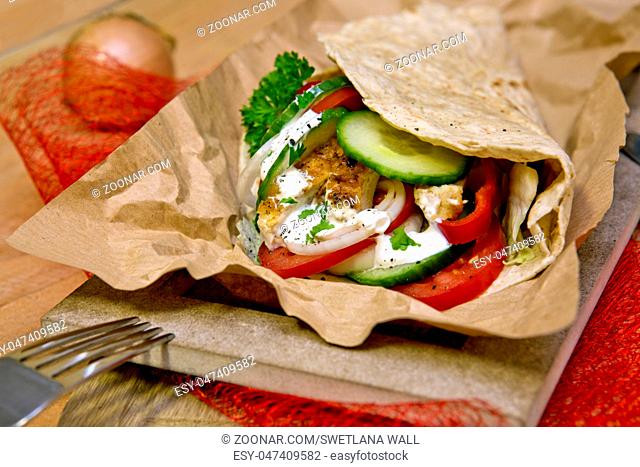 Tortilla wrap with chicken and fresh vegetables.Closeup of tasty kebab with vegetables and chicken