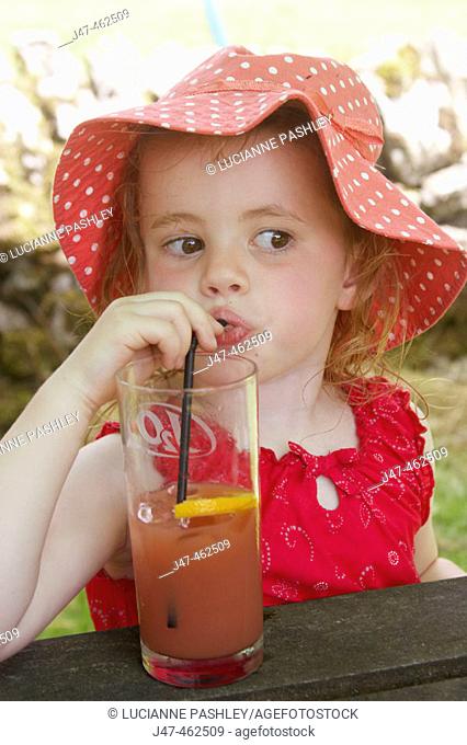 3 year old girl in a big floppy red hat, drinking through a straw