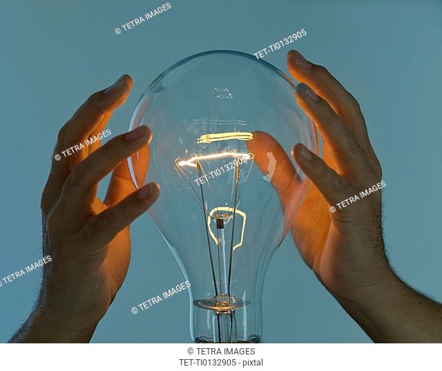 Hands cupped around large light bulb