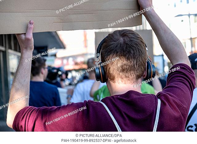 19 April 2019, Lower Saxony, Hannover: With banners and headphones a participant takes part in the demonstration against the dance ban on Good Friday