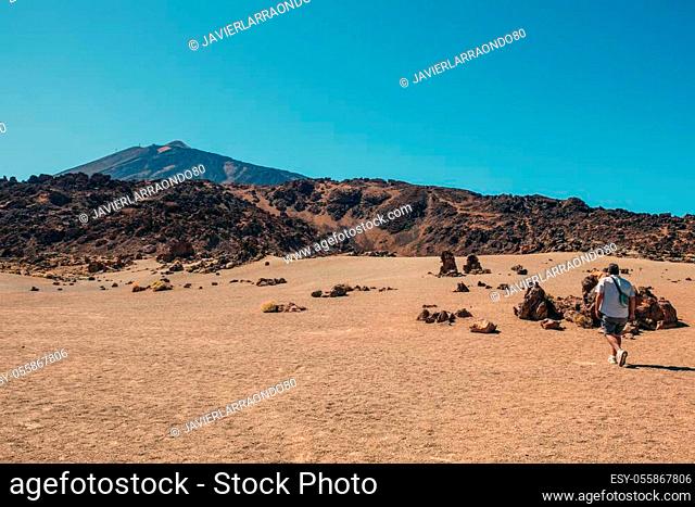 Man walking on the lonely lunar landscapes of Tenerife, colorful landscape under the blue sky. Vacation and explore concept. Copy space