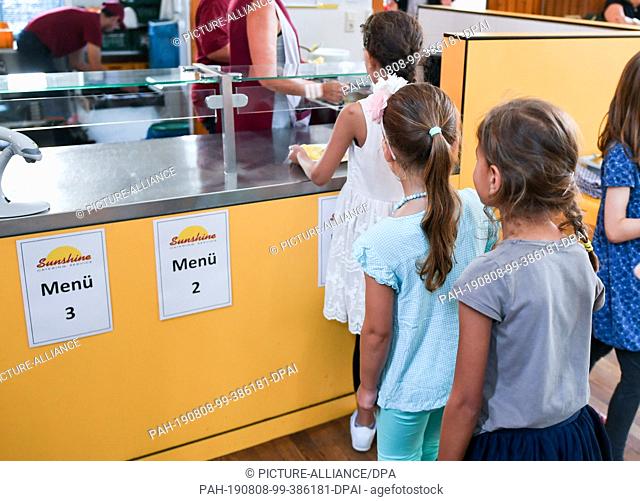 07 August 2019, Berlin: Before lunch, pupils stand in the cafeteria in the primary school on the Wuhlheide in the queue in front of the food counter