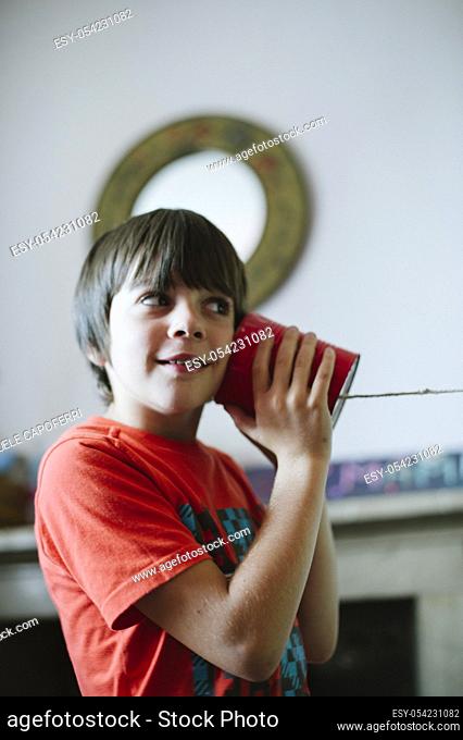 Child playing with wireless phone built with cans and string wire