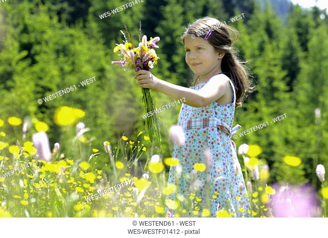 Girl with bunch of flowers in summer meadow