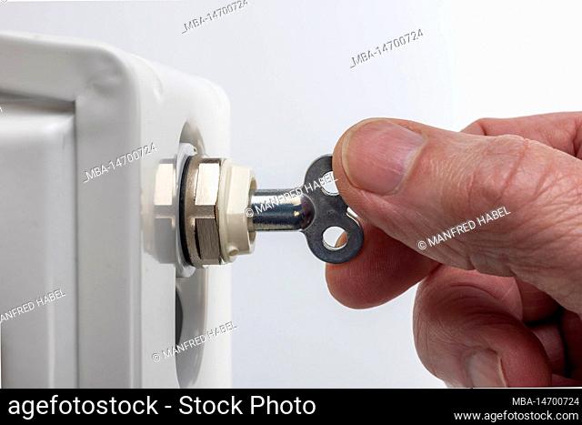 Man hand with bleeder key, bleeder valve, radiator, symbol image, bleed radiator, radiator will not warm gurgles, white background