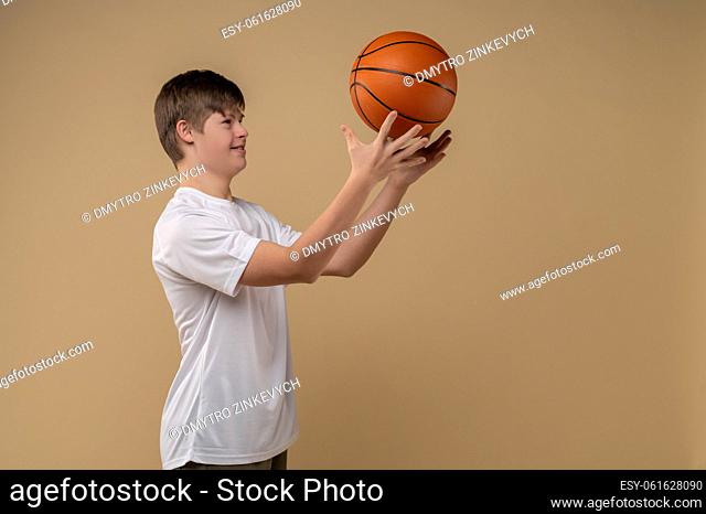 Smiling focused cute teenage boy throwing the round rubber game ball up during the workout