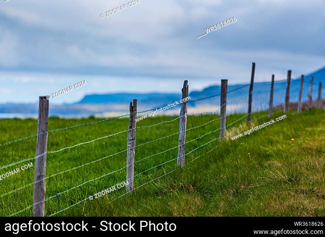 green meadow with a fence and a cloudy sky on Iceland