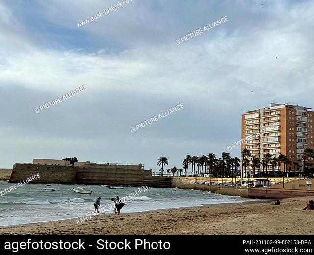 02 November 2023, Spain, Cádiz: People walking along La Caleta beach in Cadiz. Photo: Benedikt von Imhoff/dpa. - Cádiz/Andalusia/Spain