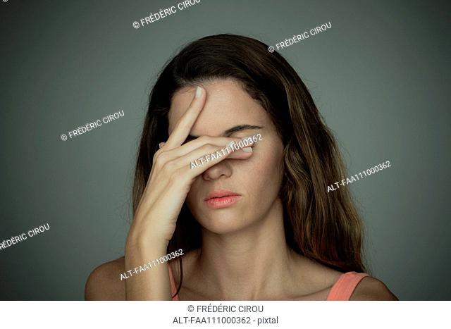 Young woman covering her eyes with one hand