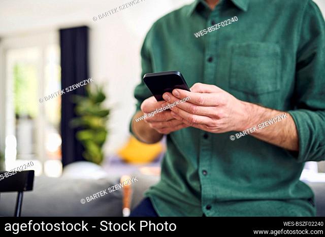 Man using smartphone leaning on couch
