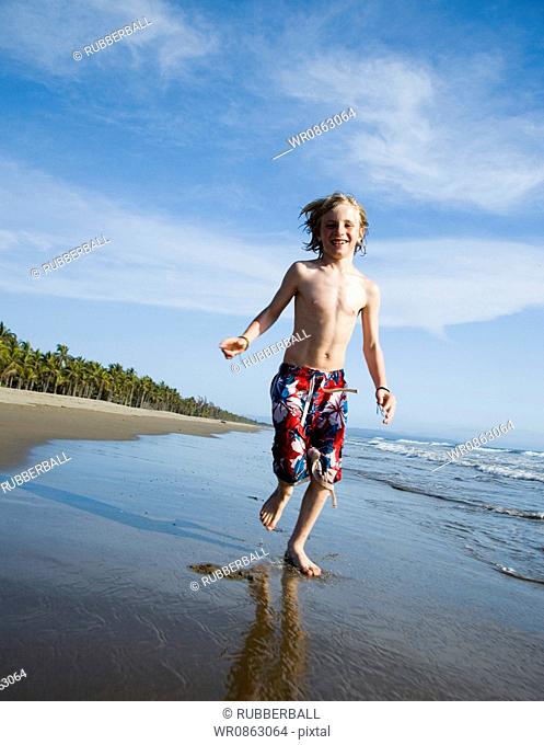 Boy running at the beach with a boogie board