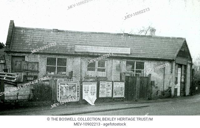 Old fire station - Black and white lantern slide. Long single storey building, posters on fence. Part of Box 399. Boswell Collection