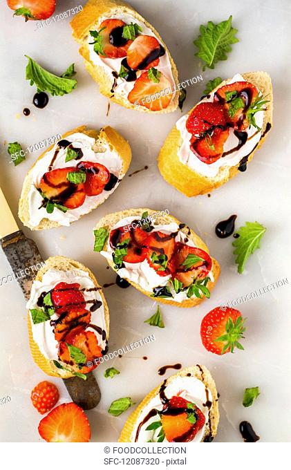 Slices of baguette with strawberries, basil, balsamic vinegar and goats' cheese