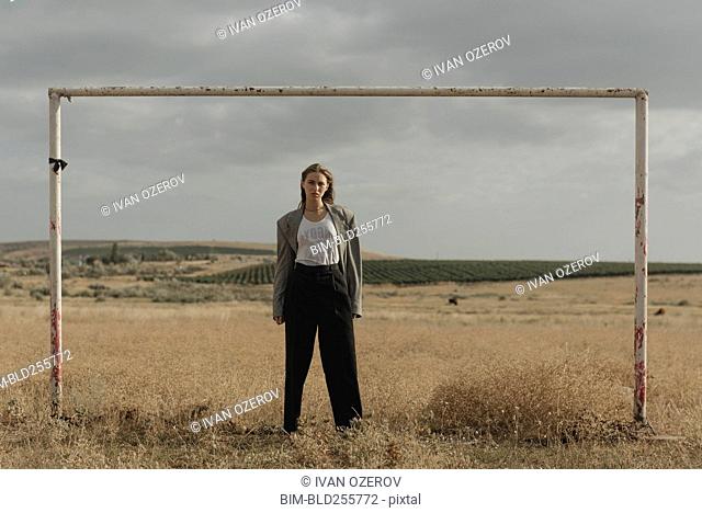 Serious location woman standing in worn soccer goal