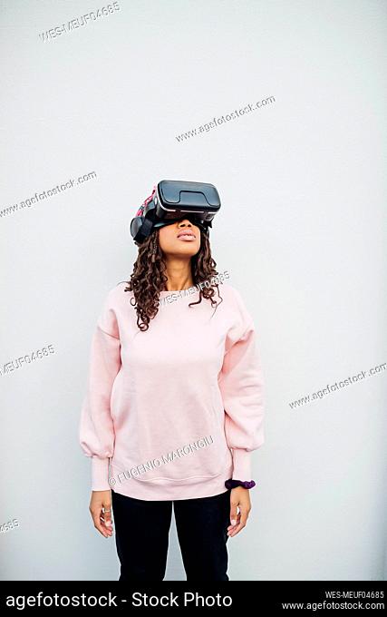 Woman using virtual reality headset in front of white wall