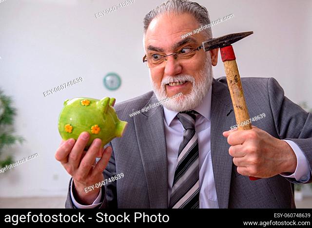 Old employee holding hammer in budget planning concept