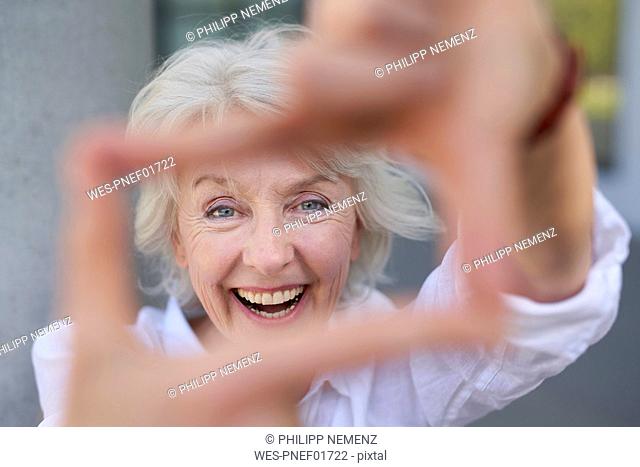 Portrait of laughing mature woman shaping frame with her fingers