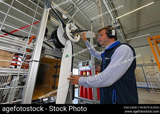 11 August 2023, Brandenburg, Strausberg: Alexander Behrens, development engineer at APUS GmbH, stands in front of a hydrogen aircraft engine he developed