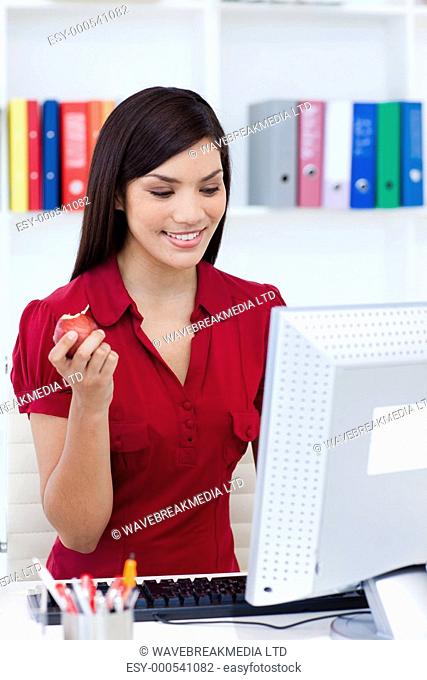 Smiling businesswoman holding a red apple at her desk