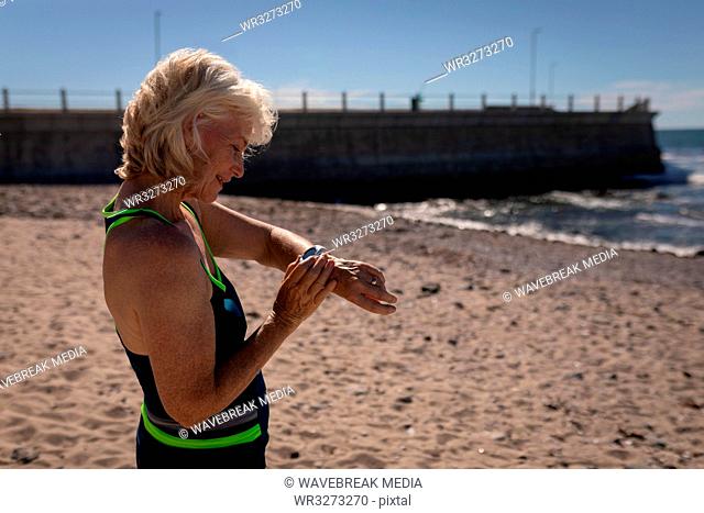 Active senior woman using smartwatch on the beach