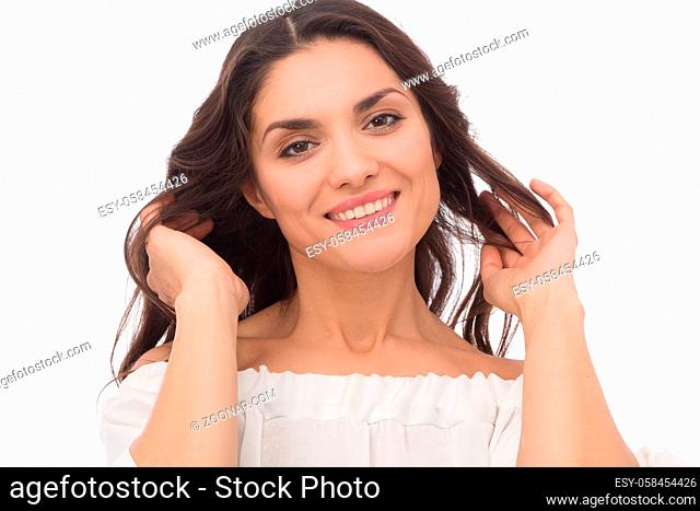Young female brunette smiling on camera and touching her curly hair. Mid age woman over 35 years old beauty concept