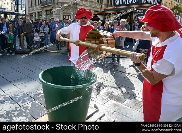 23 September 2023, Saxony-Anhalt, Halle (Saale): The traditional Bornknecht race is held in Halle's market square. With a wooden trough water must be...