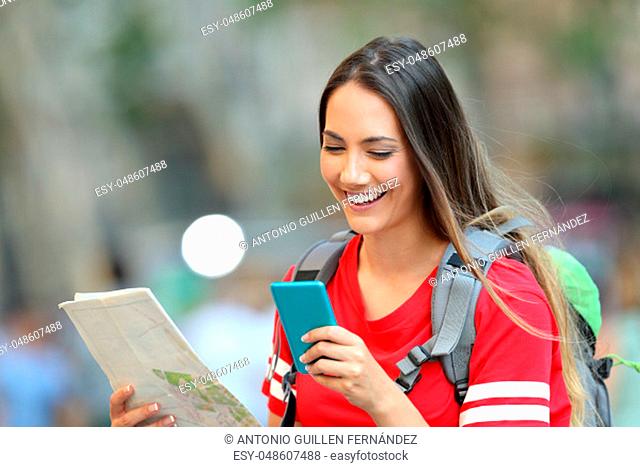 Happy teen tourist consulting online information on a smart phone walking on the street