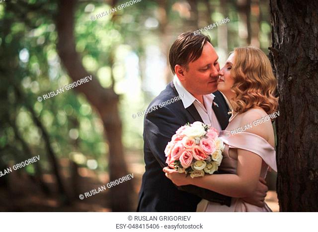 bride and groom kiss on the background of trees and forest