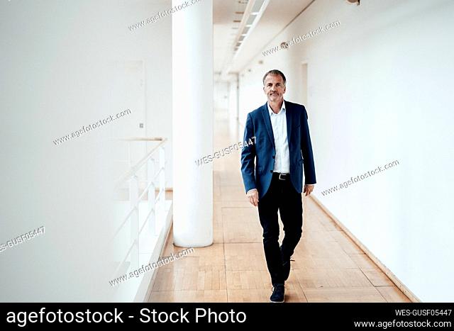 Serious male entrepreneur walking in corridor at office