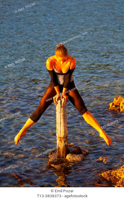 Ballerina performing in shallow water lit by warm evening sunset sidelight