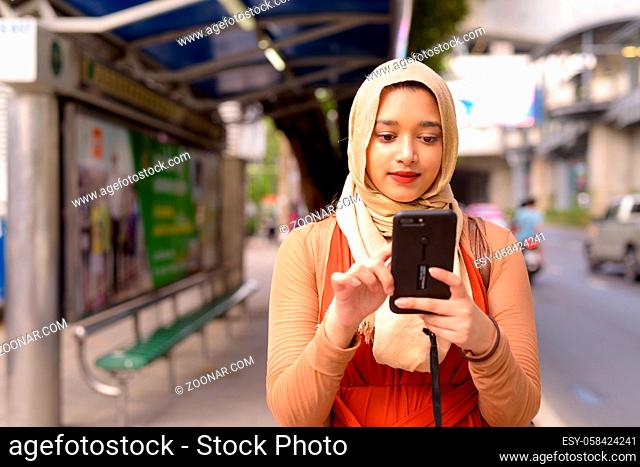 Portrait of young beautiful Indian Muslim woman with hijab at the bus stop in the city