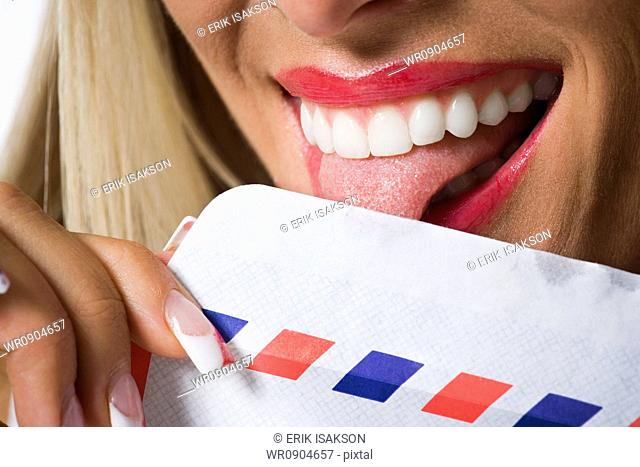 Close-up of a young woman licking an envelope
