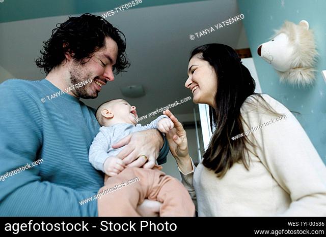 Happy mother and father playing with baby boy at home
