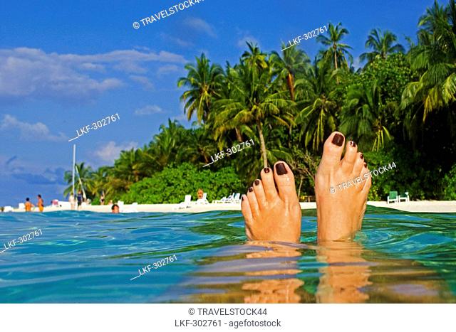 Womens feet, Palm trees at the beach of Biyadhoo Island, Indian Ocean, South Male Atoll, Maldives