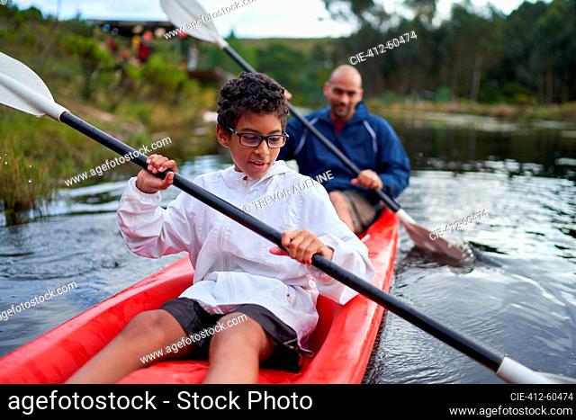Father and son kayaking on river