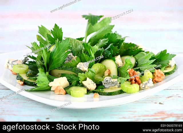 Celery leaves and stalks salad with fresh cucumber slices, blue cheese, crushed nuts