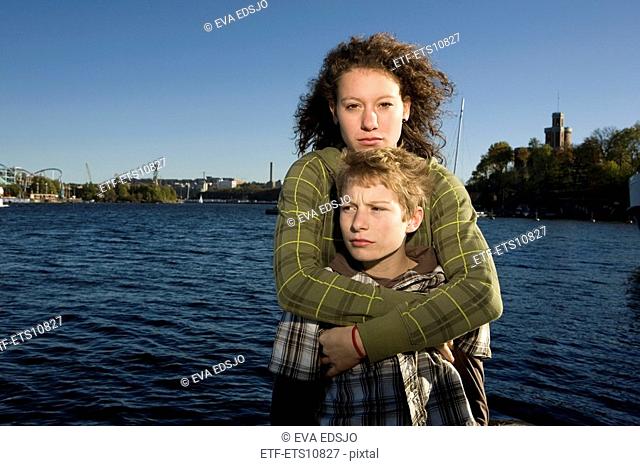 Sister hugging her brother with water in the background Sweden