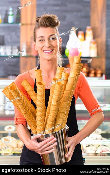 Young saleswoman in an ice cream parlor with many cones for ice cream cornets
