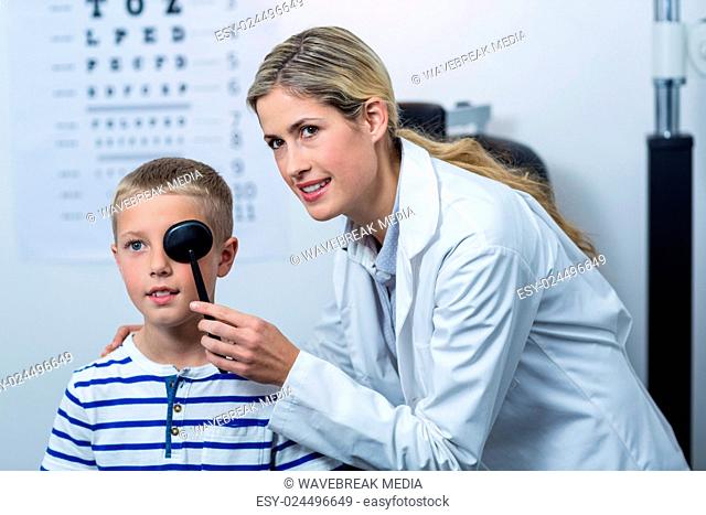 Female optometrist examining young patient with medical equipment