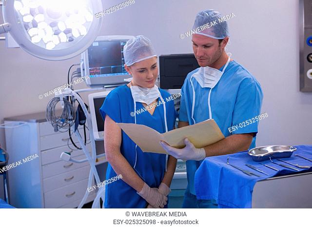 Male and female nurse having discussion over file in operation theater