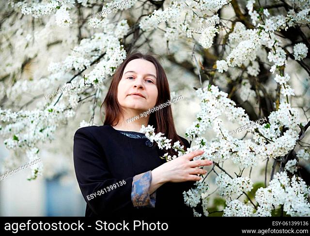 Woman in the park on the background of flowering spring tree. Selective focus