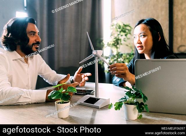 Mature businessman discussing with colleague over wind turbine model