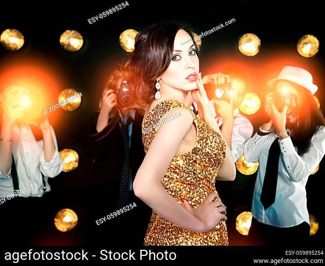 Superstar woman wearing golden shining dress posing to paparazzi